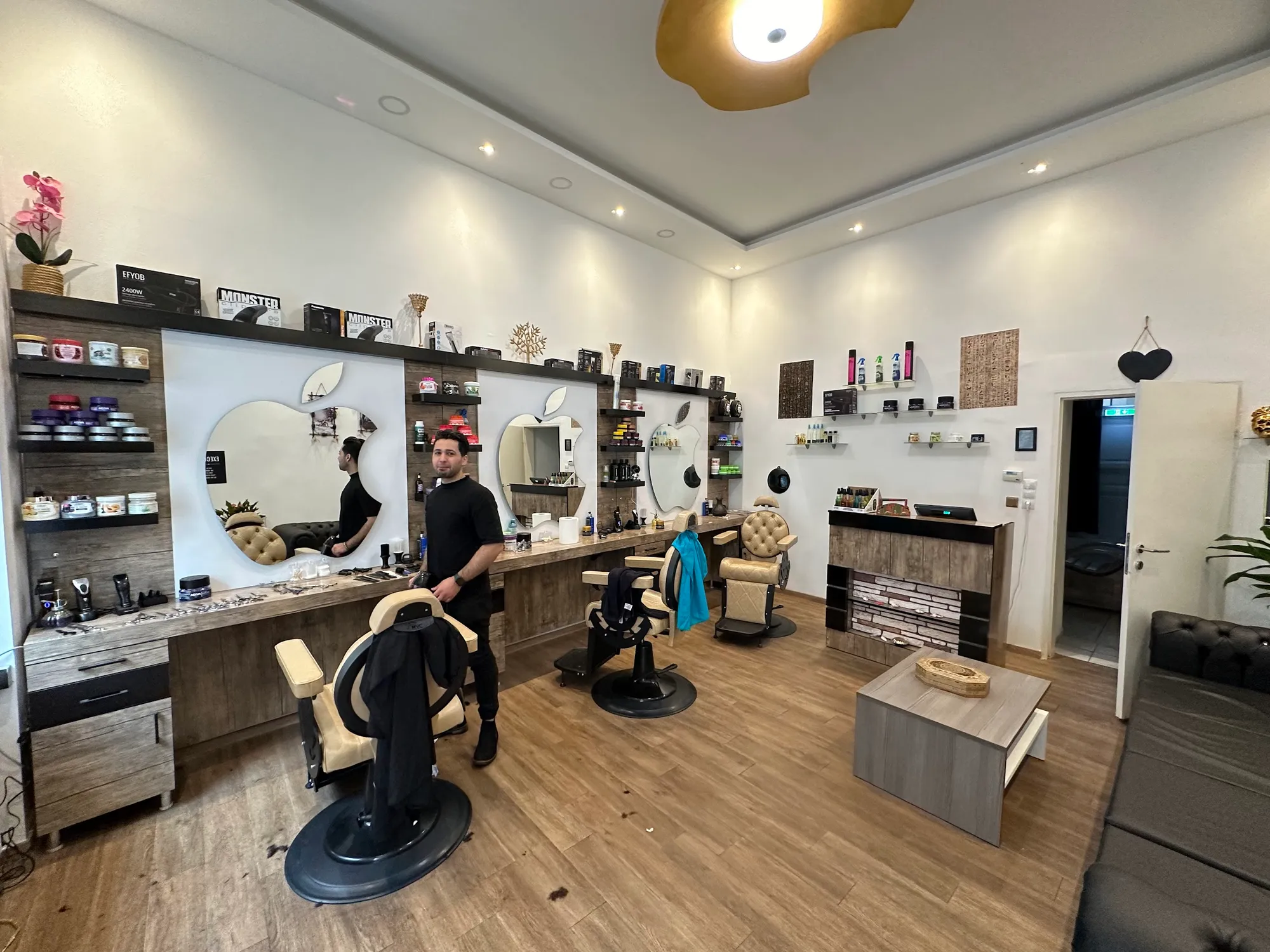 Der helle Salon mit Holzboden, Barberstühlen, Empfangstheke und Ledersofa
